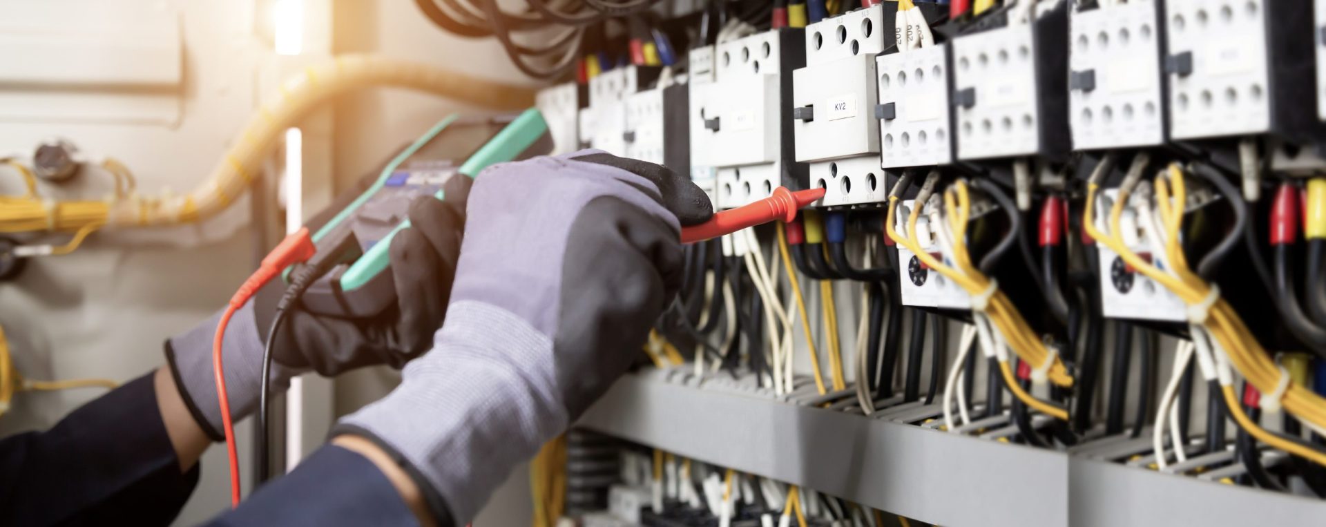 Electrician testing currents on a circuit board with a device.
